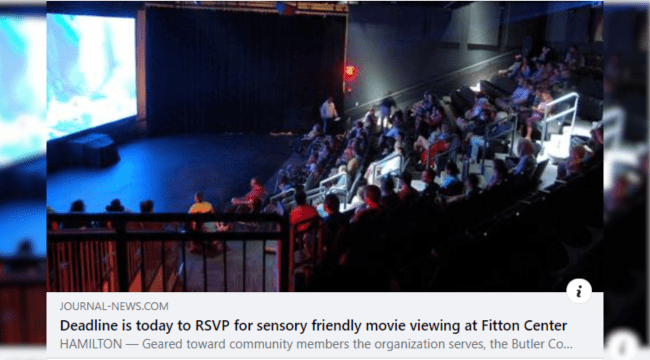 A movie theater has most seats filled with the crowd watching the big screen. The image is not clear enough to discern any details on the movie screen.